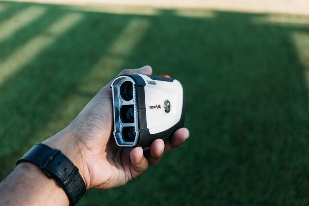Un golfeur utilisant un télémètre laser sur un parcours de golf pendant une compétition.